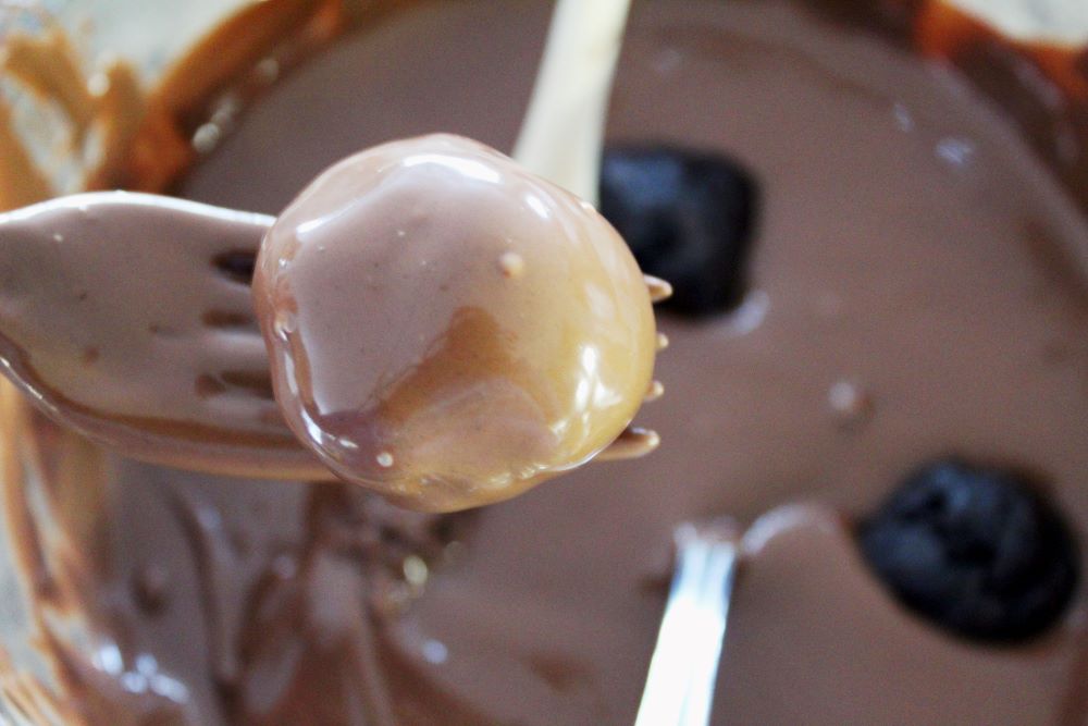 dipping brownie cheesecake truffles in chocolate almond bark 1