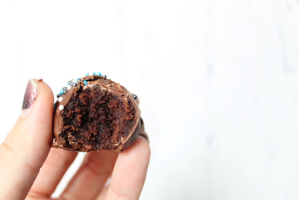 single closeup of bitten brownie cheesecake truffle in hand 1