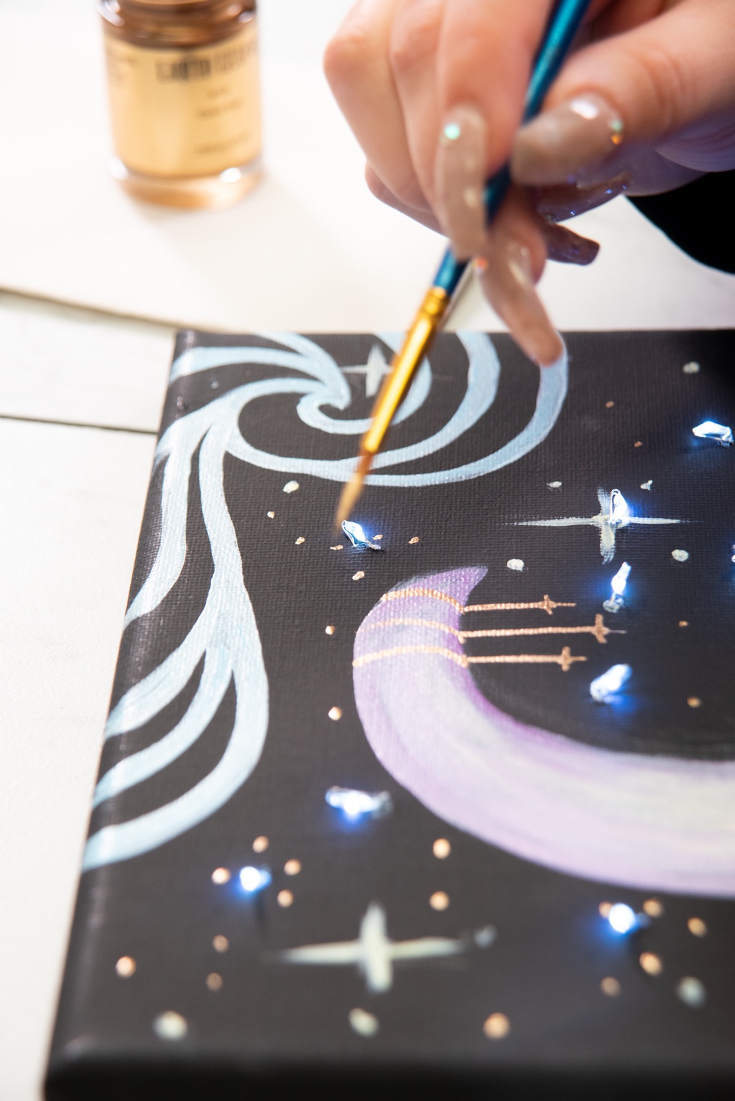 continue to add stars in gilding on the moon painting