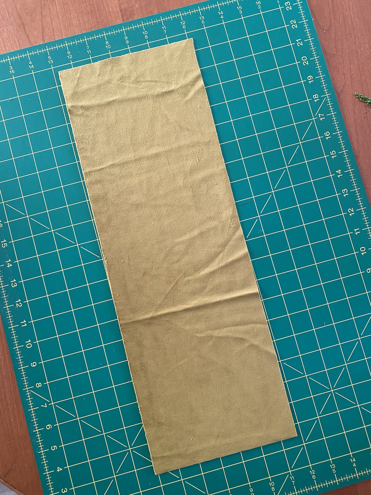 A long strip of chartreuse fabric sitting on a green cutting mat